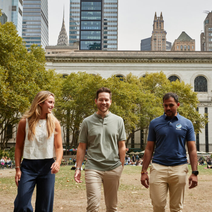 Three Stavtar employees talk and walk together in a park.